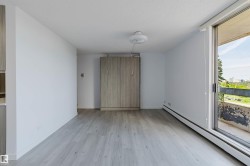 Light wood-finish flooring complements the neutral wall color of this spacious interior, featuring a built-in cabinet and sliding glass door with balcony access - 