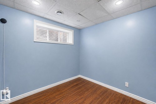 Room featuring wood-finish flooring, a drop ceiling with recessed lighting, and a window with white blinds - 5 Cypress Link, Fort Saskatchewan, AB - Indoor Photo Showing Other Room