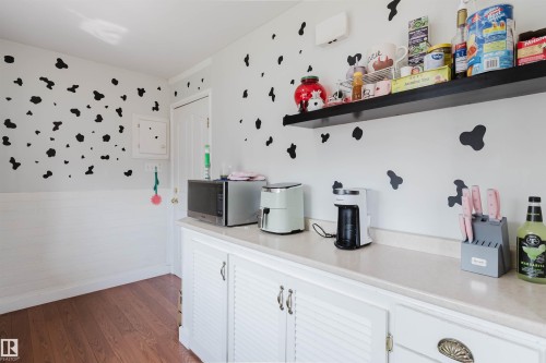 Kitchenette featuring white cabinetry with louvered doors, a light-colored countertop, and a dark floating shelf - 10955 72 Avenue Nw, Edmonton, AB - Indoor Photo Showing Kitchen