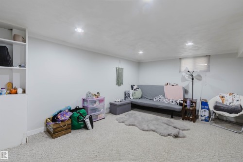 Spacious room featuring light-colored carpeting, recessed lighting, a white painted window trim, and built-in shelving - 10955 72 Avenue Nw, Edmonton, AB - Indoor Photo Showing Basement