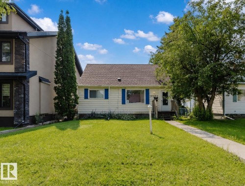 Front exterior featuring light-colored siding, a dark shingle roof, and blue window shutters - 10955 72 Avenue Nw, Edmonton, AB - Outdoor With Facade