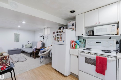 Compact kitchen area featuring white cabinetry, a white electric range, and a white refrigerator - 10955 72 Avenue Nw, Edmonton, AB - Indoor Photo Showing Kitchen