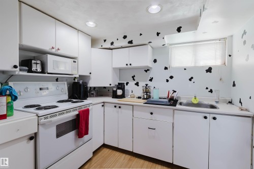 Compact kitchen featuring white cabinetry, a white electric range, and a stainless steel sink - 10955 72 Avenue Nw, Edmonton, AB - Indoor Photo Showing Kitchen