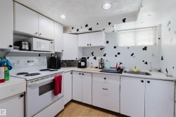 Compact kitchen featuring white cabinetry, a white electric range, and a stainless steel sink - 
