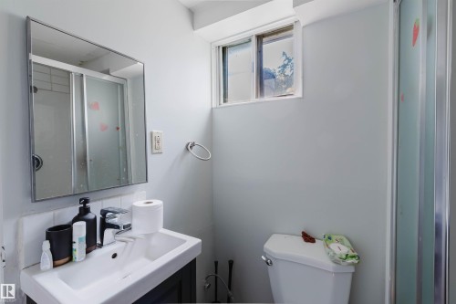 Bathroom featuring a vanity with a white basin sink, framed mirror, and a window - 10955 72 Avenue Nw, Edmonton, AB - Indoor Photo Showing Bathroom
