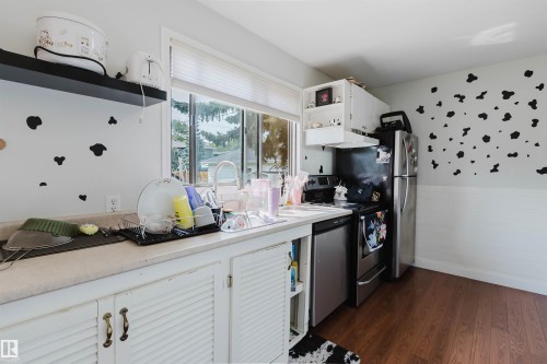 Kitchen space featuring a stainless steel refrigerator, stainless steel electric range with overhead cabinetry, and wood-finish flooring - 10955 72 Avenue Nw, Edmonton, AB - Indoor Photo Showing Kitchen