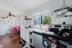 Kitchen featuring wood-finish flooring, white cabinetry, a built-in electric range, and a window with horizontal blinds - 