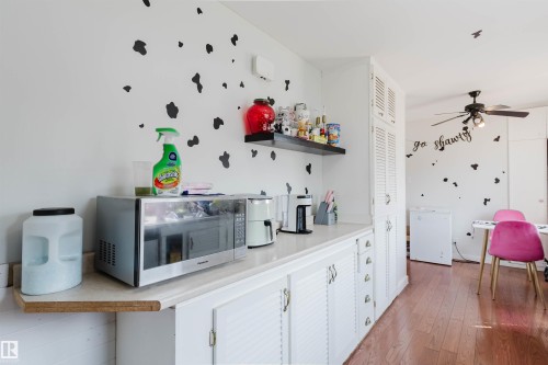 Kitchen area featuring white cabinetry with louvered doors, light-toned countertops, and a dark floating shelf - 10955 72 Avenue Nw, Edmonton, AB - Indoor Photo Showing Other Room
