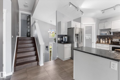 Contemporary kitchen with white cabinetry, stainless steel appliances, and dark countertops - 4009 158 Avenue Nw, Edmonton, AB - Indoor Photo Showing Kitchen