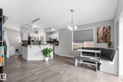Open-concept living space featuring wood-finish tile flooring, recessed lighting, and a contemporary kitchen with white cabinetry - 4009 158 Avenue Nw, Edmonton, AB - Indoor