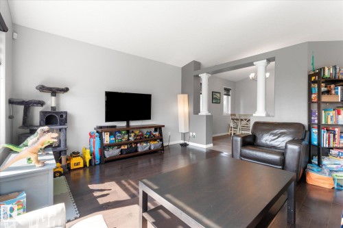 Living area featuring dark wood-finish flooring, light grey painted walls, and a vaulted ceiling - 4009 158 Avenue Nw, Edmonton, AB - Indoor Photo Showing Living Room