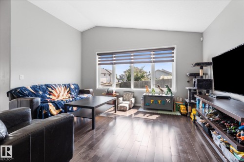 Spacious living area featuring wood-finish flooring, a large window with horizontal blinds, and light gray wall paint - 4009 158 Avenue Nw, Edmonton, AB - Indoor Photo Showing Living Room