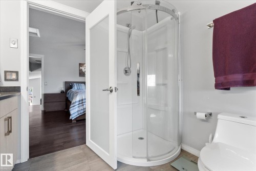 Bathroom featuring a curved glass shower enclosure, white toilet, and tile flooring - 4009 158 Avenue Nw, Edmonton, AB - Indoor Photo Showing Bathroom