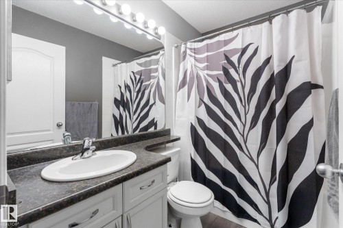 Bathroom featuring a vanity with an integrated sink, dark countertop, and lower cabinetry - 4009 158 Avenue Nw, Edmonton, AB - Indoor Photo Showing Bathroom