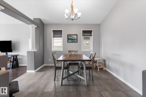 Dining area featuring wood-finish flooring, two large windows, and a multi-light chandelier - 4009 158 Avenue Nw, Edmonton, AB - Indoor Photo Showing Dining Room