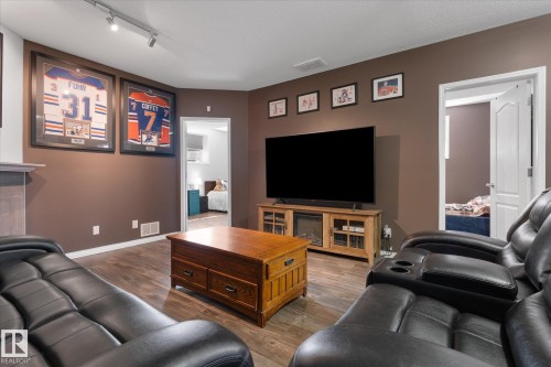 Open living area featuring wood-finish flooring, recessed lighting, and a built-in media console with an electric fireplace - 4009 158 Avenue Nw, Edmonton, AB - Indoor Photo Showing Living Room