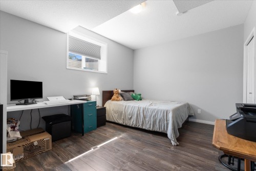 Room featuring wood-finish flooring, light gray walls, a window with a cellular shade, and a white door - 4009 158 Avenue Nw, Edmonton, AB - Indoor Photo Showing Bedroom