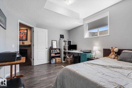 Spacious room with durable wood-finish flooring, neutral gray walls, and a large window providing natural light - 4009 158 Avenue Nw, Edmonton, AB - Indoor Photo Showing Bedroom