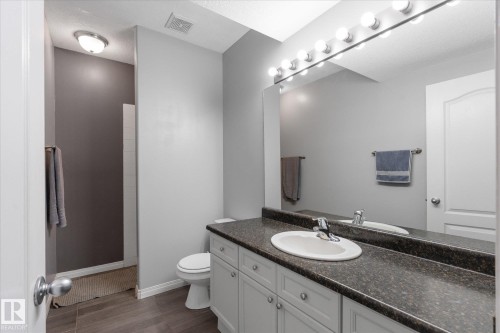Bathroom featuring a single vanity with an integrated sink, dark speckled countertop, and light-toned cabinetry - 4009 158 Avenue Nw, Edmonton, AB - Indoor Photo Showing Bathroom