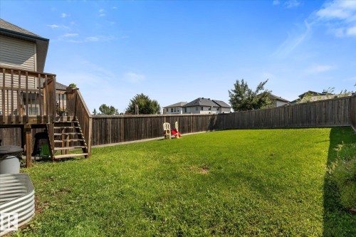 Expansive backyard with a large grassy area, privacy fencing, and a raised wood deck featuring stairs to the yard - 4009 158 Avenue Nw, Edmonton, AB - Outdoor
