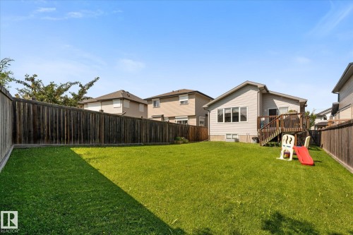 Expansive grassy backyard featuring a full privacy fence, a multi-level wood deck, and an exterior door providing direct access - 4009 158 Avenue Nw, Edmonton, AB - Outdoor With Backyard