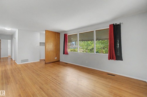 Spacious room featuring wood-finish flooring, light grey walls, and a large multi-pane window - 8215 149 Street Nw, Edmonton, AB - Indoor Photo Showing Other Room