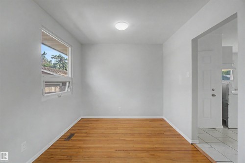 Neutral toned interior with wood-finish flooring, a white window frame, and a flush mount ceiling light - 8215 149 Street Nw, Edmonton, AB - Indoor Photo Showing Other Room