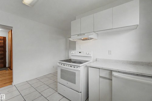 Kitchen featuring white tile flooring, white cabinetry, solid surface countertops, a white electric range, and a white dishwasher - 8215 149 Street Nw, Edmonton, AB - Indoor Photo Showing Kitchen