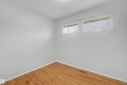 Interior space featuring wood-finish flooring, light gray wall paint, and white trim - 8215 149 Street Nw, Edmonton, AB - Indoor Photo Showing Other Room