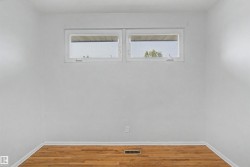 Bright room featuring wood-finish flooring, white painted walls, and two horizontal windows - 