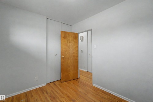 Hardwood flooring throughout, neutral wall paint, and a built-in closet with sliding doors - 8215 149 Street Nw, Edmonton, AB - Indoor Photo Showing Other Room