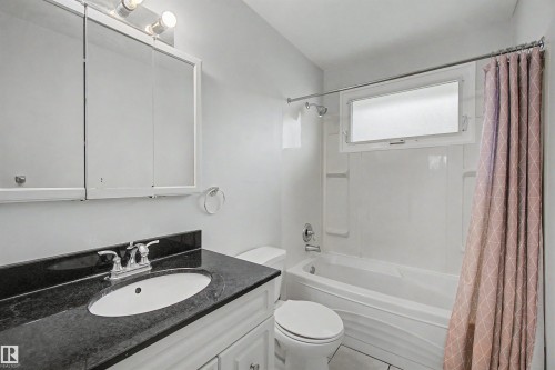 Bathroom featuring a white vanity with a dark countertop, white oval sink, and chrome faucet - 8215 149 Street Nw, Edmonton, AB - Indoor Photo Showing Bathroom