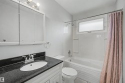 Bathroom featuring a white vanity with a dark countertop, white oval sink, and chrome faucet - 