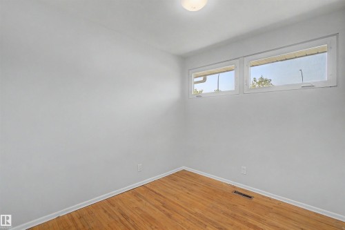 Bright room featuring wood-finish flooring, white walls, and a pair of clerestory windows - 8215 149 Street Nw, Edmonton, AB - Indoor Photo Showing Other Room