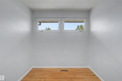 Room with light gray walls, wood-finish flooring, and white baseboards - 