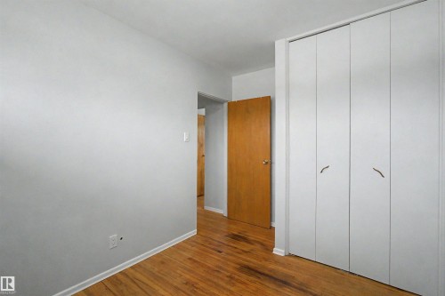 White bi-fold closet doors with curved brass hardware - 8215 149 Street Nw, Edmonton, AB - Indoor Photo Showing Other Room