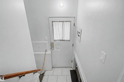 White interior door with a paneled window, featuring a light-colored curtain - 8215 149 Street Nw, Edmonton, AB - Indoor Photo Showing Other Room