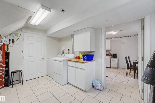 Laundry area featuring a washer, dryer, built-in cabinetry, and wood-finish countertop - 8215 149 Street Nw, Edmonton, AB - Indoor Photo Showing Laundry Room
