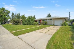 Ranch-style exterior with an attached single-car garage, a concrete driveway, and a red entry door - 