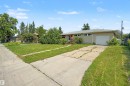 Ranch-style exterior with an attached single-car garage, a concrete driveway, and a red entry door - 8215 149 Street Nw, Edmonton, AB  - Outdoor 