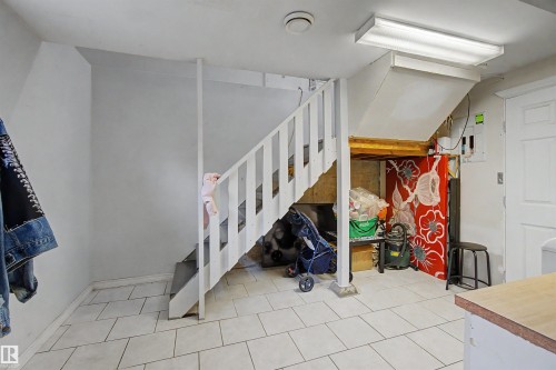 White painted staircase with wood treads and white risers, featuring a partial baluster and handrail - 8215 149 Street Nw, Edmonton, AB - Indoor Photo Showing Other Room