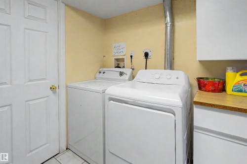 Utility area featuring a white six-panel door with brass hardware, tile flooring, and light-colored walls - 8215 149 Street Nw, Edmonton, AB - Indoor Photo Showing Laundry Room