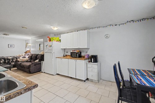 Efficient kitchen area featuring white cabinetry, light countertops, and a white refrigerator - 8215 149 Street Nw, Edmonton, AB - Indoor Photo Showing Kitchen