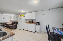 Efficient kitchen area featuring white cabinetry, light countertops, and a white refrigerator - 