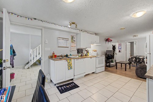 Kitchen space featuring white cabinetry, a built-in dishwasher, and a white electric range - 8215 149 Street Nw, Edmonton, AB - Indoor Photo Showing Kitchen