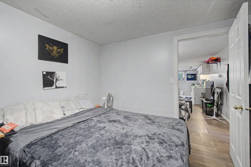 Comfortable bedroom featuring wood-finish flooring, generous natural light from multiple windows, and direct access to a walk-in closet with shelving - 8215 149 Street Nw, Edmonton, AB - Indoor Photo Showing Bedroom
