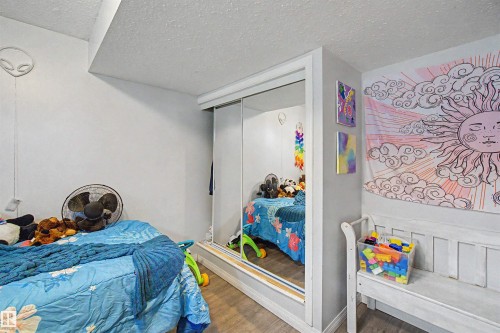 Mirrored sliding closet doors with white trim, wood-finish flooring, and a white ceiling - 8215 149 Street Nw, Edmonton, AB - Indoor Photo Showing Bedroom