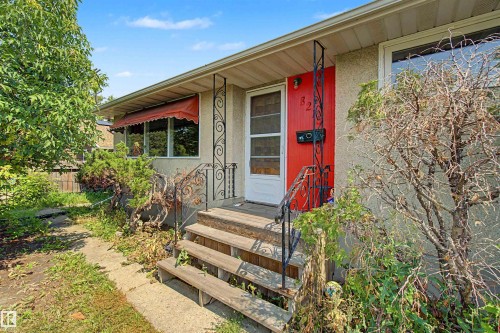 Front entry featuring a bright red door, white storm door, and decorative black wrought iron railings - 8215 149 Street Nw, Edmonton, AB - Outdoor