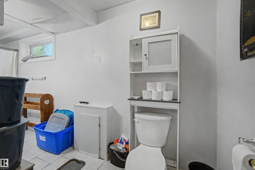 Bathroom featuring a white toilet, white tile flooring, and a white over-the-toilet storage cabinet with a closed door and open shelves - 8215 149 Street Nw, Edmonton, AB - Indoor