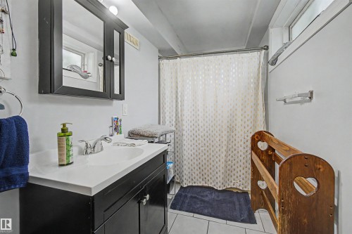 Bathroom featuring a dark wood-finish vanity with a white integrated sink, a mirrored medicine cabinet with integrated lighting, and a shower area - 8215 149 Street Nw, Edmonton, AB - Indoor Photo Showing Bathroom